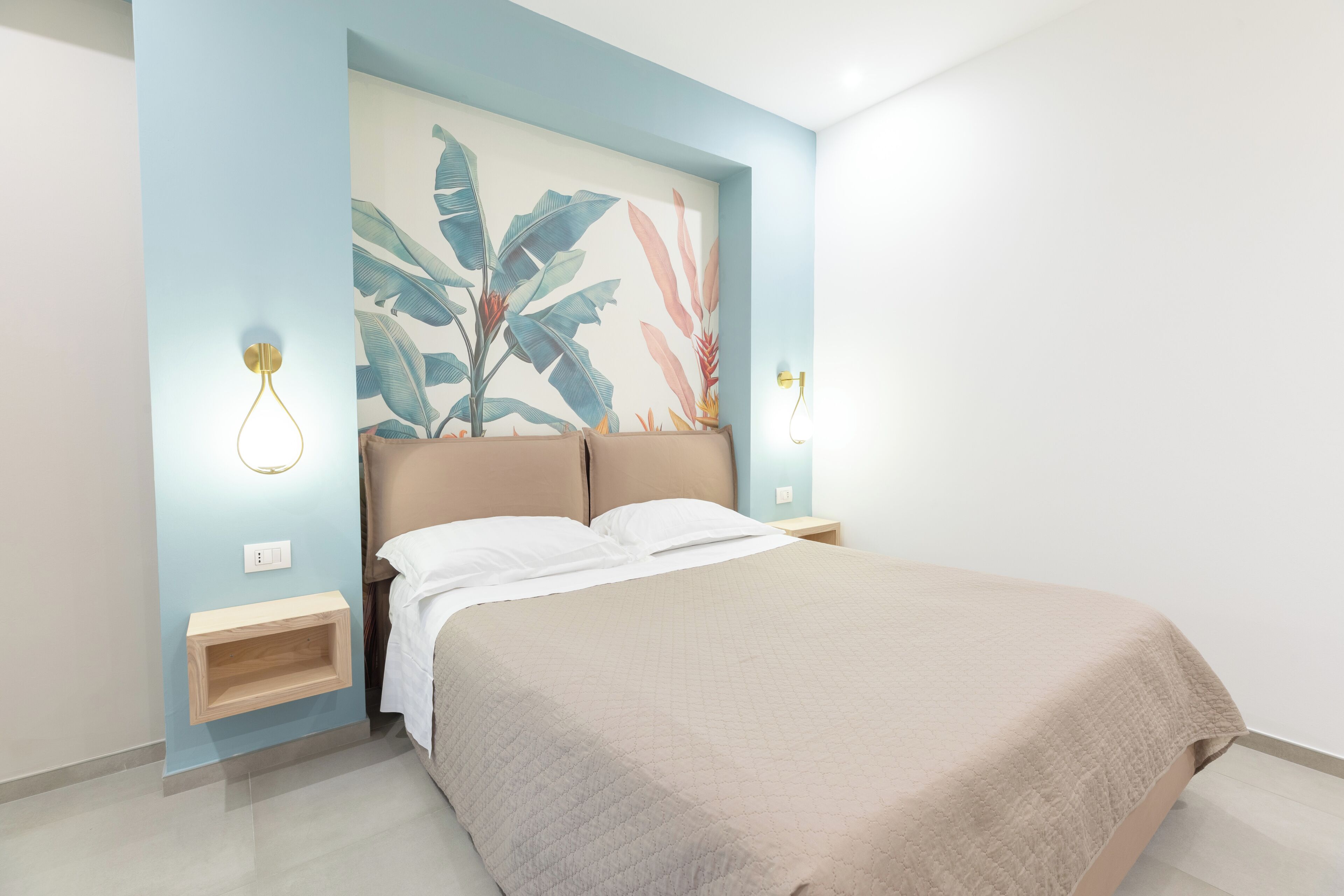 A bedroom with a bed, a wall-mounted shelf, and a wall art piece.