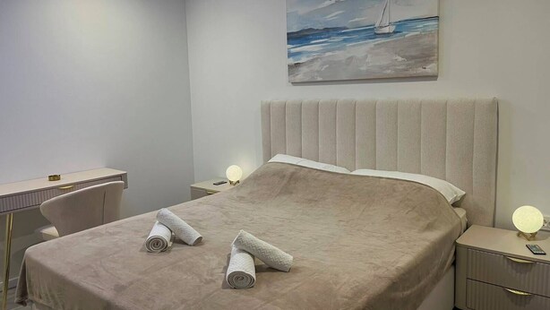 Una camera da letto con un letto, comodini, una scrivania e un quadro raffigurante una barca a vela appeso al muro.