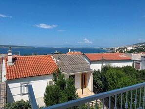A coastal residential area with terracotta-tiled roofs, white walls, and a clear view of the sea.