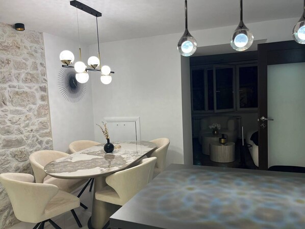 A dining area with a round table, chairs, and pendant lighting.