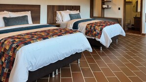 A hotel room with two beds, wooden beams, a tiled floor, and a bathroom visible through an open door. - Hotel Cala (Cucaita)