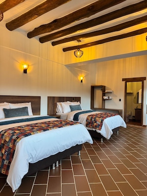 A hotel room with two beds, wooden beams, a tiled floor, and a bathroom visible through an open door. - Hotel Cala (Cucaita)