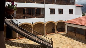 A two-story building with a tiled roof, a central staircase, and a courtyard with stone flooring. - Hotel Cala (Cucaita)
