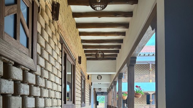 A corridor with a brick wall, a tiled floor, and a sign indicating an exit. - Hotel Cala (Cucaita)