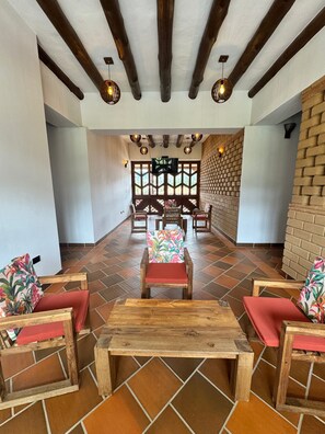 Un vestíbulo amplio con una mesa de centro de madera, sillones con cojines rojos y una pared de ladrillo.