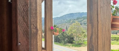 A wooden balcony with a view of a road and distant hills.