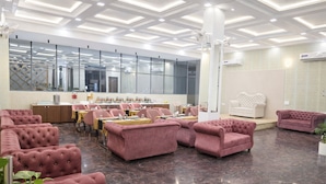 A modern hotel lobby with plush seating, a reception desk, and large windows.