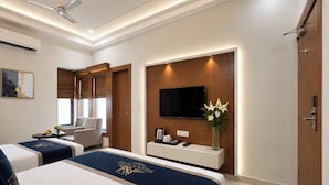 A hotel room with two beds, a TV, a desk, a chair, and a wardrobe.