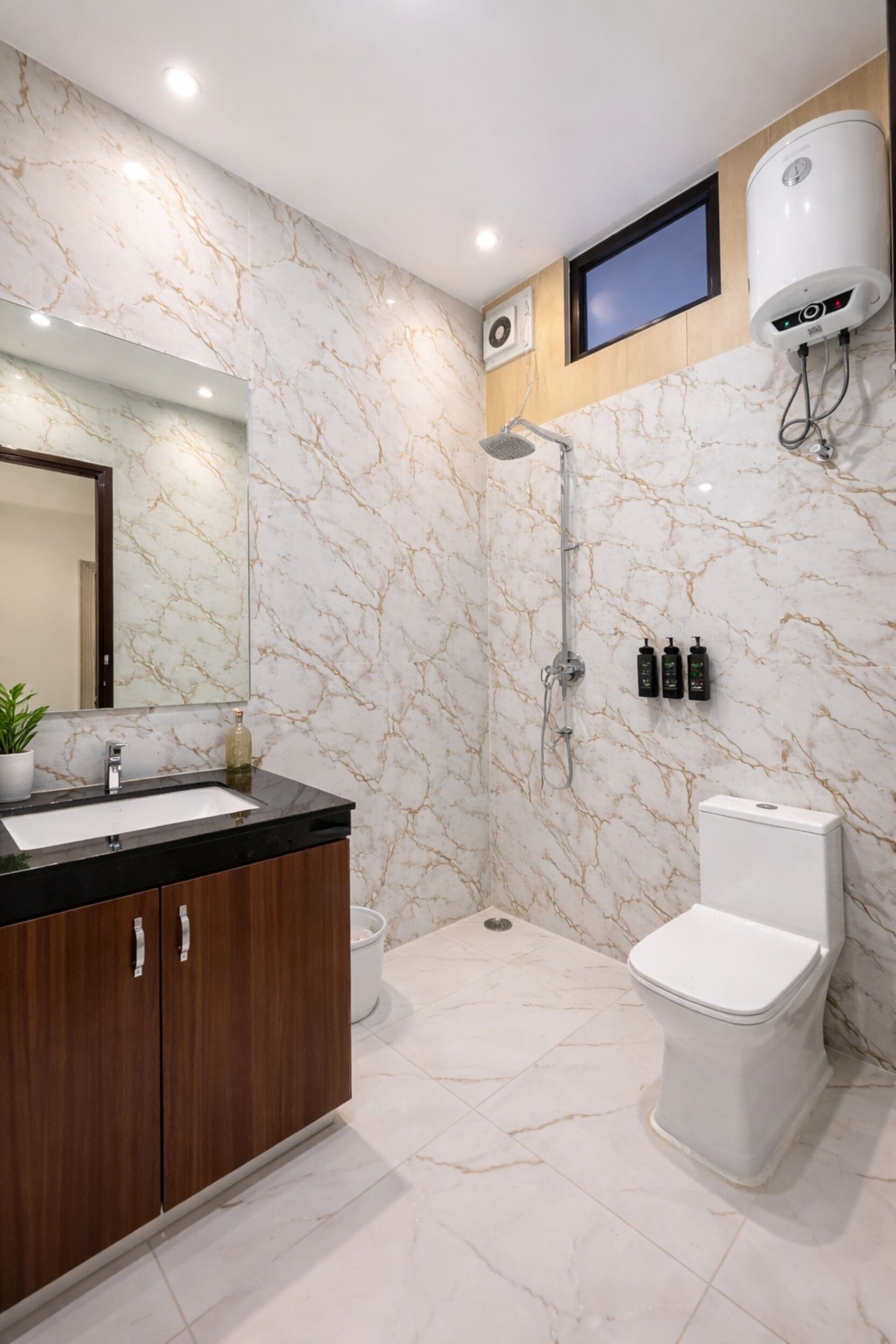 A modern bathroom with a marble backsplash, a built-in sink, a toilet, and a shower.