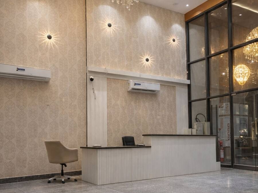 Un área de recepción con una gran araña, un mostrador de recepción y una decoración de estilo moderno.