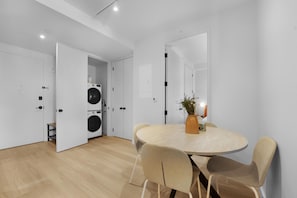 Una cocina moderna con lavadora integrada, una mesa redonda con sillas y un espejo grande en la pared.
