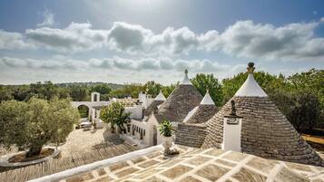 Un patio con edificios de piedra, un pérgola y plantas en macetas.