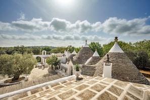 A courtyard with stone buildings, a pergola, and potted plants.