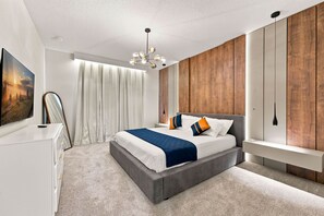 A modern bedroom with a large bed, a bedside table, a mirror, and a wooden accent wall. - Orlando Most Incredible Themed 10BR Villa (Four Corners)