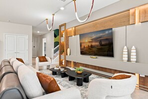 Una sala de estar moderna con un sofá seccional, una mesa de centro y un televisor de pantalla plana montado en la pared.