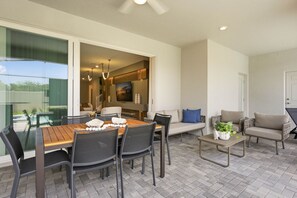 Un patio al aire libre con una mesa de comedor, sillas, un sofá y una pequeña mesa de centro.