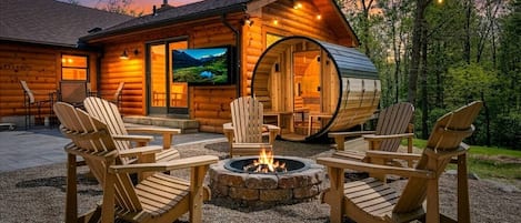 A log cabin with a fire pit and Adirondack chairs in the outdoor area.
