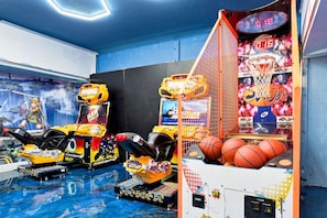 Une salle avec des jeux d’arcade, notamment une machine à pinces et des simulateurs de course.