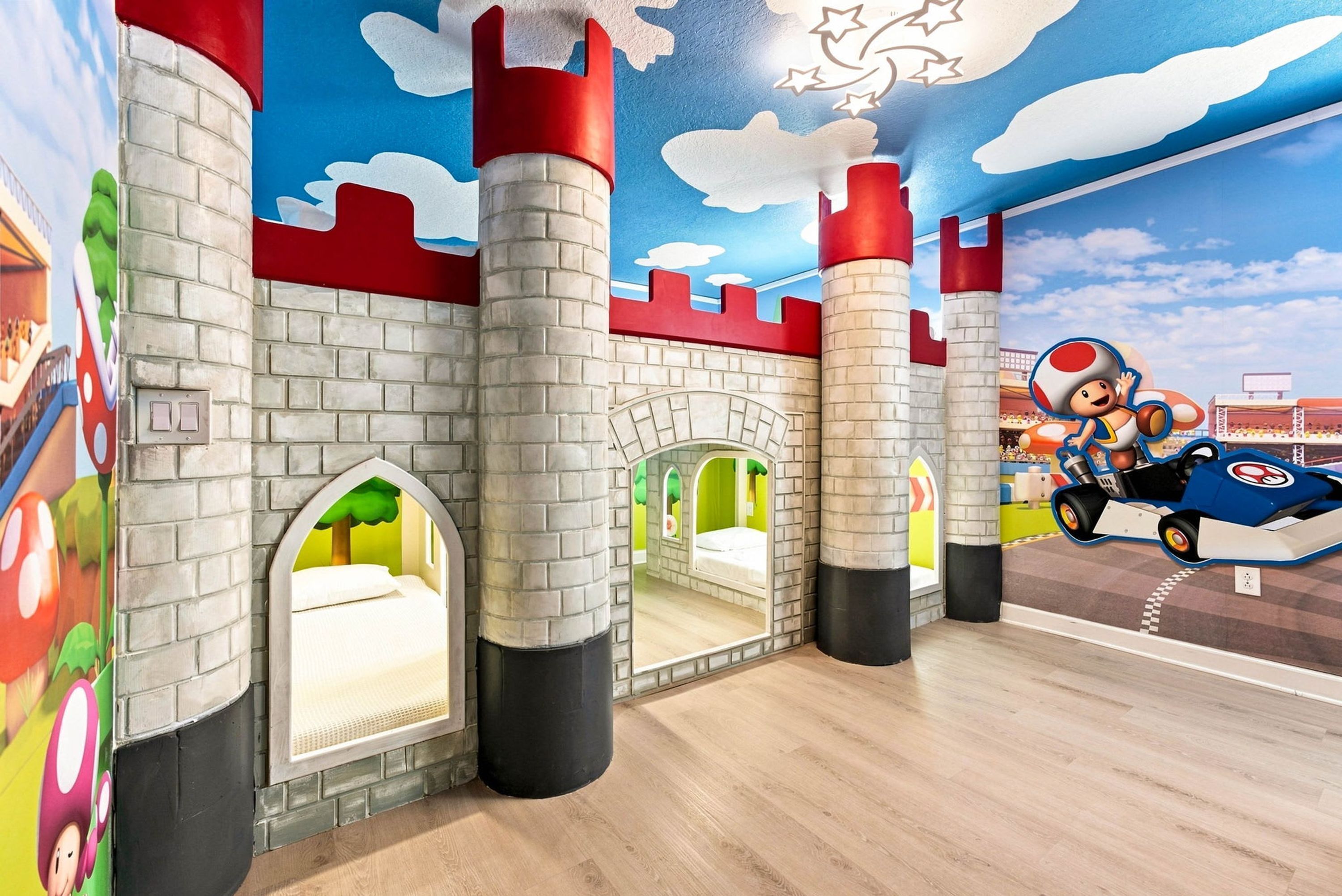 Une salle de jeux sur le thème du château, avec des murs en briques, des portes en arc de cercle et une fresque représentant un personnage de dessin animé à moto.