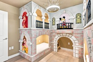 A children's playroom with a brick-patterned wall, a balcony with a railing, and a chandelier. - Themed 9BR Villa, Pool, Game Room, Champions Gate (Four Corners)