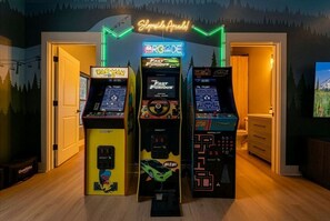 Drei Spielautomaten in einem Raum mit einem Neonzeichen darüber und einer Bergmalerei an der Wand.