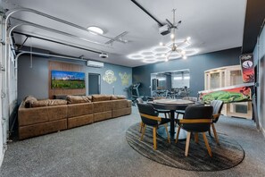 Ein modernes Interieur mit einem braunen Sofa, einem runden Tisch mit Stühlen und Trainingsgeräten.