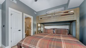 Ein Schlafzimmer mit einem Bett, einer Tür, einem Deckenventilator und einem Fenster.