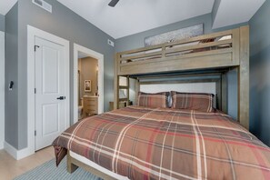 Ein Schlafzimmer mit einem Bett, einer Tür, einem Deckenventilator und einem Fenster.