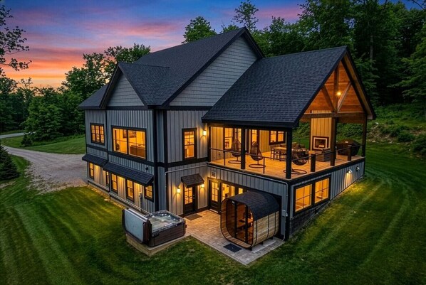 Ein zweistöckiges Haus mit einer großen Terrasse und einem Whirlpool.