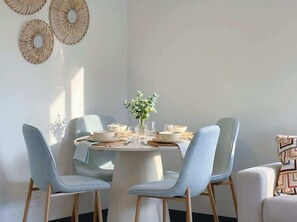 Un coin repas avec une table ronde, des chaises bleu clair et un vase rempli de fleurs.