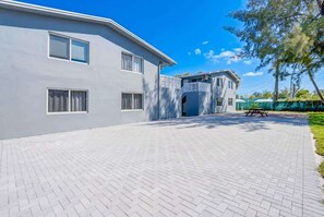 A modern building with a paved driveway, a covered entrance, and a picnic table. - Modern Retreat Near Beach, Airport & Las Olas (Fort Lauderdale)