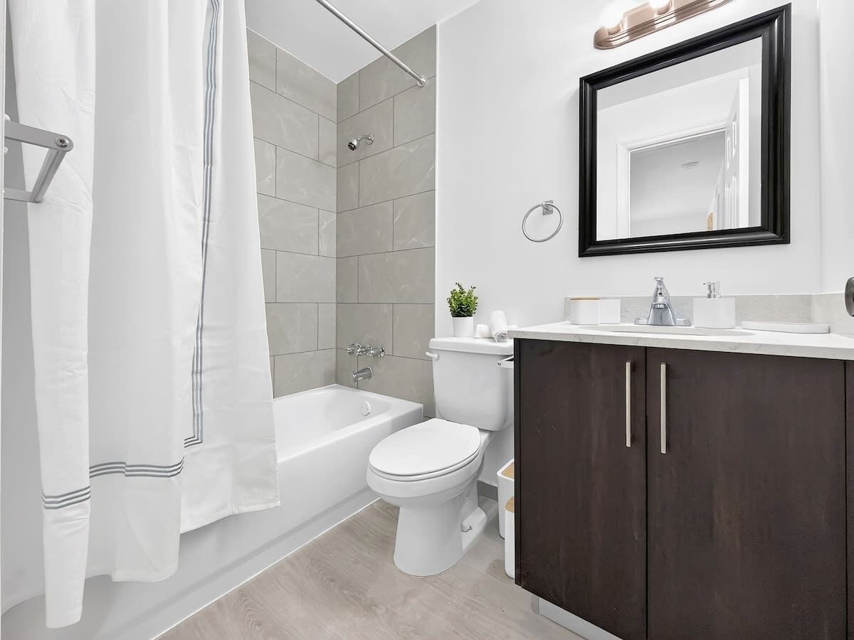 A modern bathroom with a bathtub, toilet, and dark wooden cabinets.