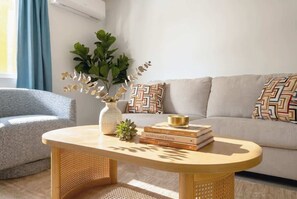A living room with a sofa, a coffee table, a plant, and patterned cushions. - Modern 2BR Near Beach, Airport & Las Olas (Fort Lauderdale)