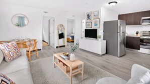 Un salon moderne comprenant un canapé, une table basse et un coin repas avec des chaises.