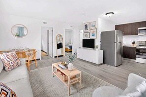 A modern living room with a sofa, coffee table, and a dining area with chairs. - Beautiful 2BR Near Beach, Airport & Las Olas (Fort Lauderdale)