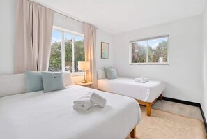 A hotel room with two beds, a window with a view of trees, and a lamp on a bedside table. - Beautiful 2BR Near Beach, Airport & Las Olas (Fort Lauderdale)