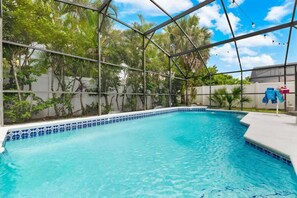 Ein Schwimmbad mit Glasveranda, umgeben von Grünflächen und einem weißen Zaun.