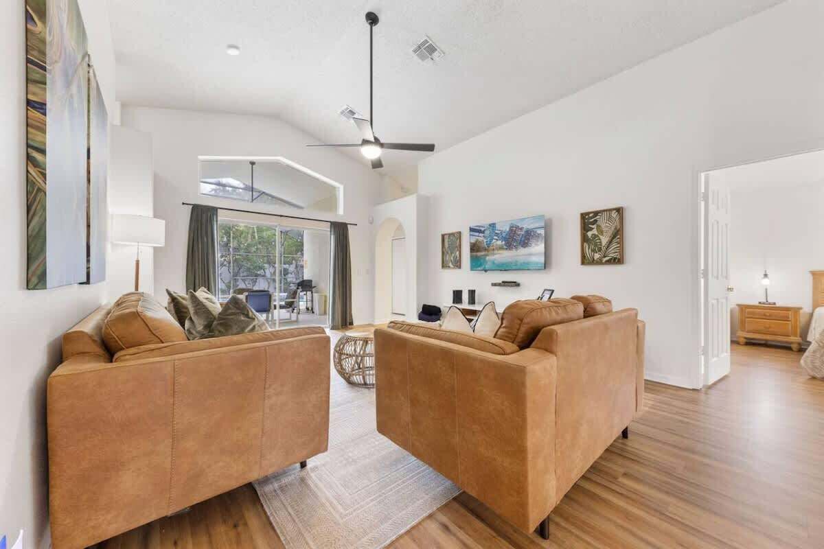 A modern living room with two sofas, a ceiling fan, and artwork on the walls.