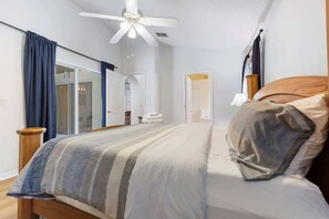 Ein Schlafzimmer mit Bett, Deckenventilator, Nachttisch und Spiegel.