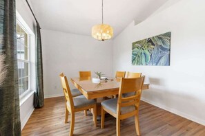 Ein Essbereich mit Holztisch und -stühlen, einer hängenden Leuchte und einem Wandbild.