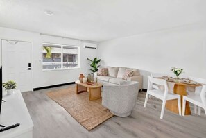Ein modernes Wohnzimmer mit Sofa, Couchtisch und Esstisch.