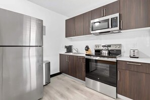 Eine moderne Küche mit Edelstahlgeräten, dunklen Holzschränken und einer weißen Arbeitsplatte.
