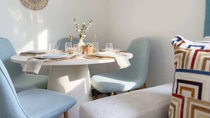 A dining area with a round table, light blue chairs, and a patterned throw on a couch. - Cozy 2BR Near Beach, Airport & Las Olas (Fort Lauderdale)