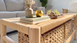 A wicker table with a woven backrest, a vase with dried flowers, a book, and a small plant on a modern sofa in a well-lit room. - Cozy 2BR Near Beach, Airport & Las Olas (Fort Lauderdale)
