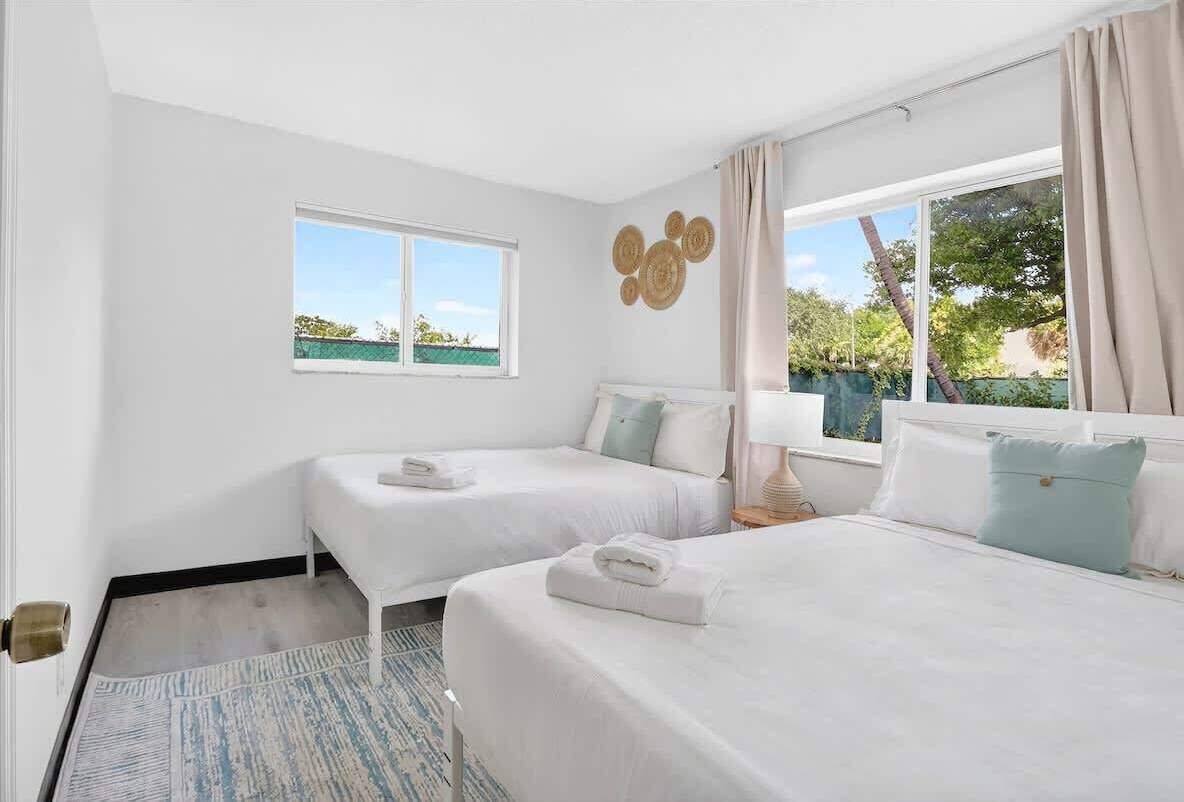 A hotel room with two beds, a window with a view, and a wall-mounted decorative item.