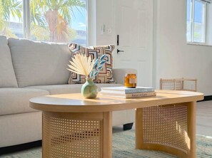 A round wooden table with a woven base, a vase with dried plants, and a stack of books. - Newly Renovated 2BR Near Beach, Airport & Las Olas (Fort Lauderdale)