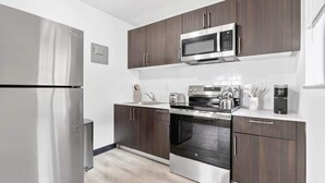 A modern kitchen with stainless steel appliances, dark wood cabinets, and a white countertop. - Inviting 2BR Near Beach, Airport & Las Olas (Fort Lauderdale)