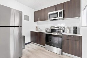 Eine moderne Küche mit Edelstahlgeräten, dunklen Holzschränken und einer weißen Arbeitsplatte.