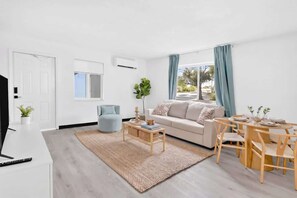 Ein modernes Wohnzimmer mit Sofa, Couchtisch und Esstisch.