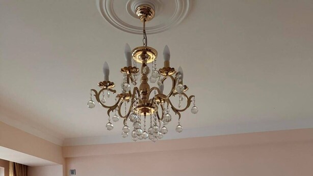 Una sala de estar con sofá, mesa de centro, candelabro y ventilador.
